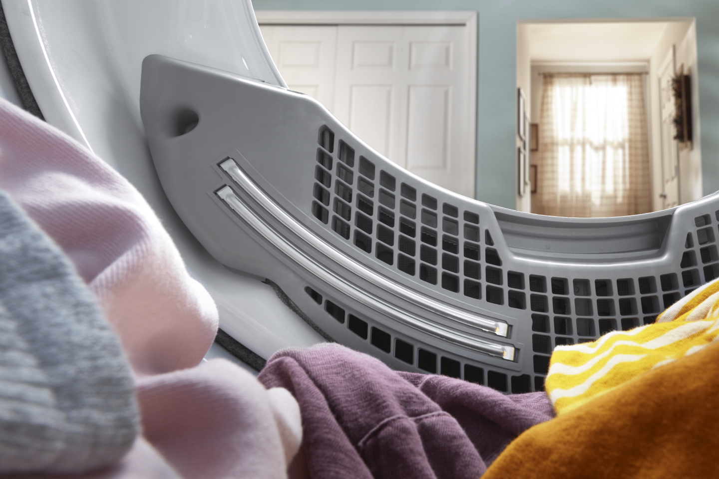 Interior shot of colorful clothes sitting in the dryer drum. 