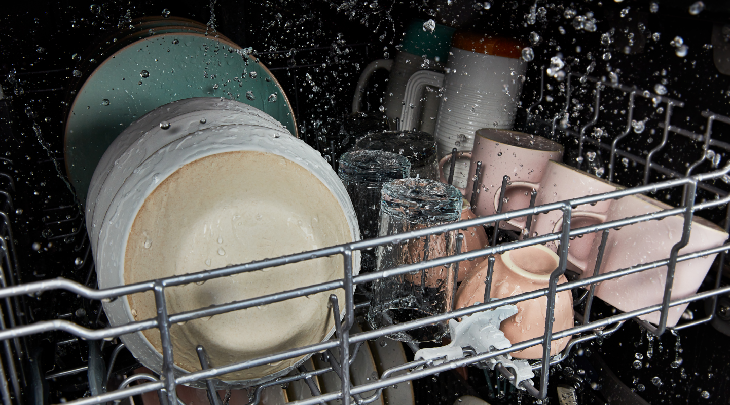 The interior of a Whirlpool® dishwasher cleaning dishes during a wash cycle.