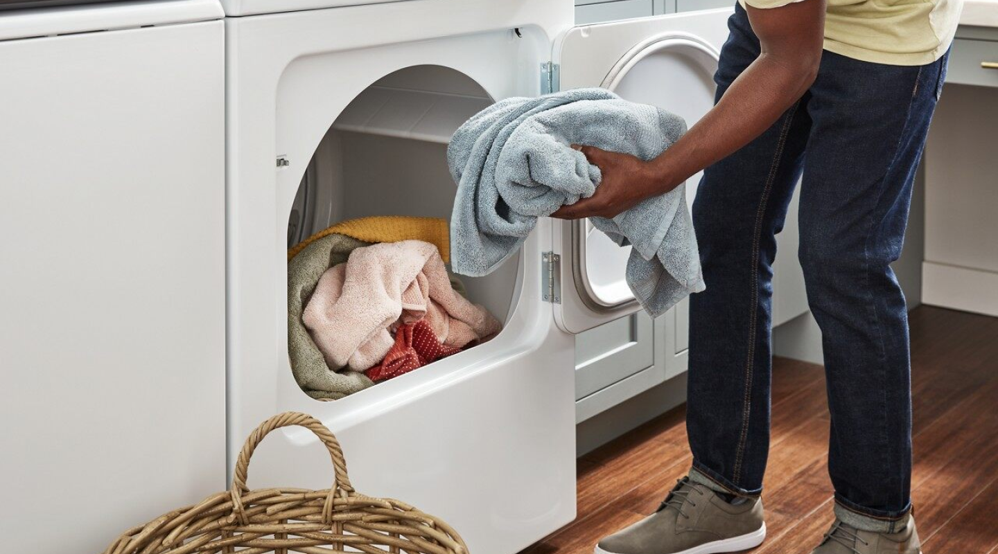 Person placing a load of towels into the dryer