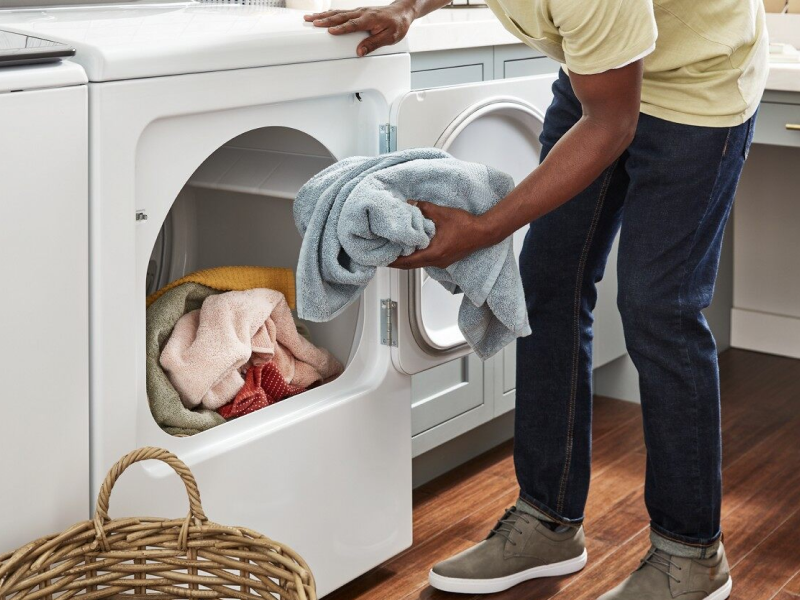 Person placing a load of towels into the dryer