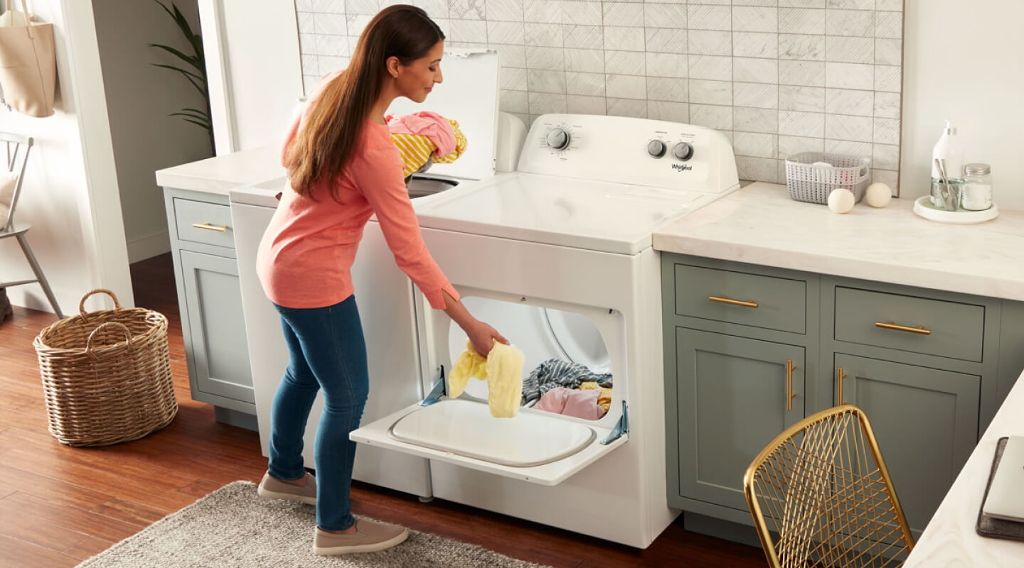 A person loading clothes into a Whirlpool® dryer