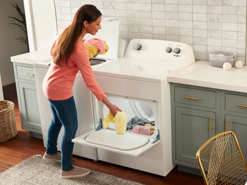 A person loading clothes into a Whirlpool® dryer
