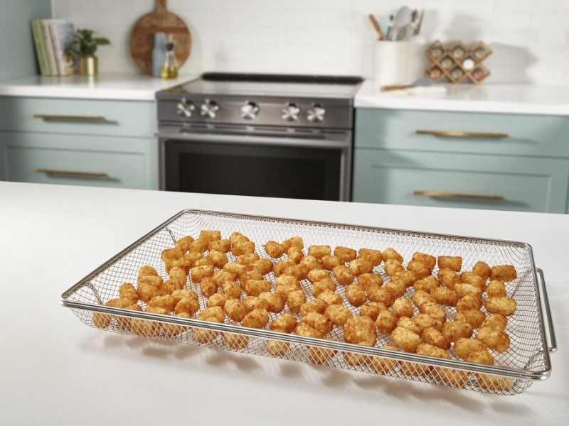 A basket with air fried food on a counter in a modern kitchen.