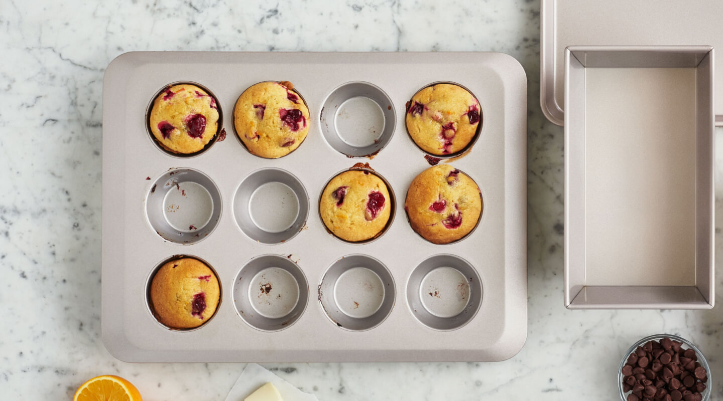 A muffin tin with cranberry muffins in 6 of the 12 cups