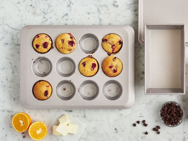 A muffin tin with cranberry muffins in 6 of the 12 cups