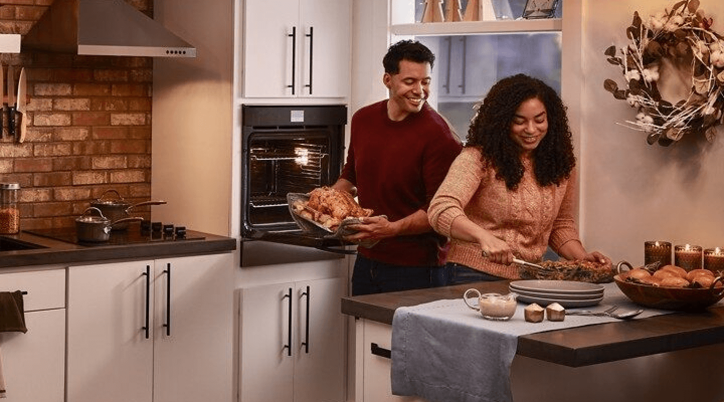 Smiling people preparing a turkey dinner in a modern kitchen