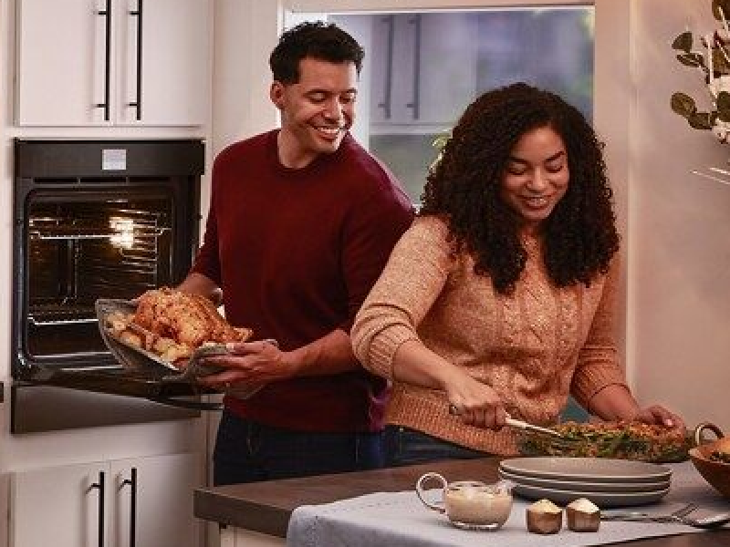 Smiling people preparing a turkey dinner in a modern kitchen
