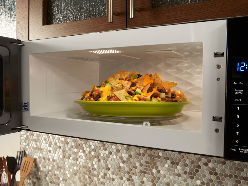 Green plate of nachos inside over-the-range microwave