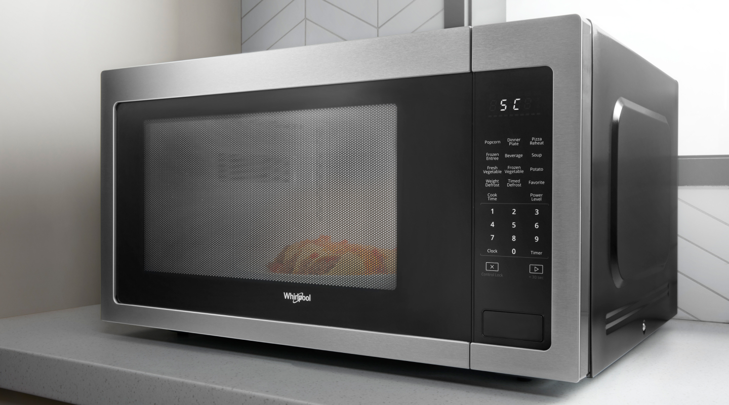 Silver and black countertop microwave from Whirlpool brand cooking food
