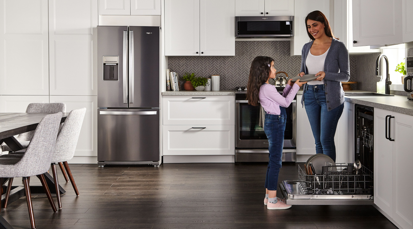 Person handing a child a clean dish in a kitchen