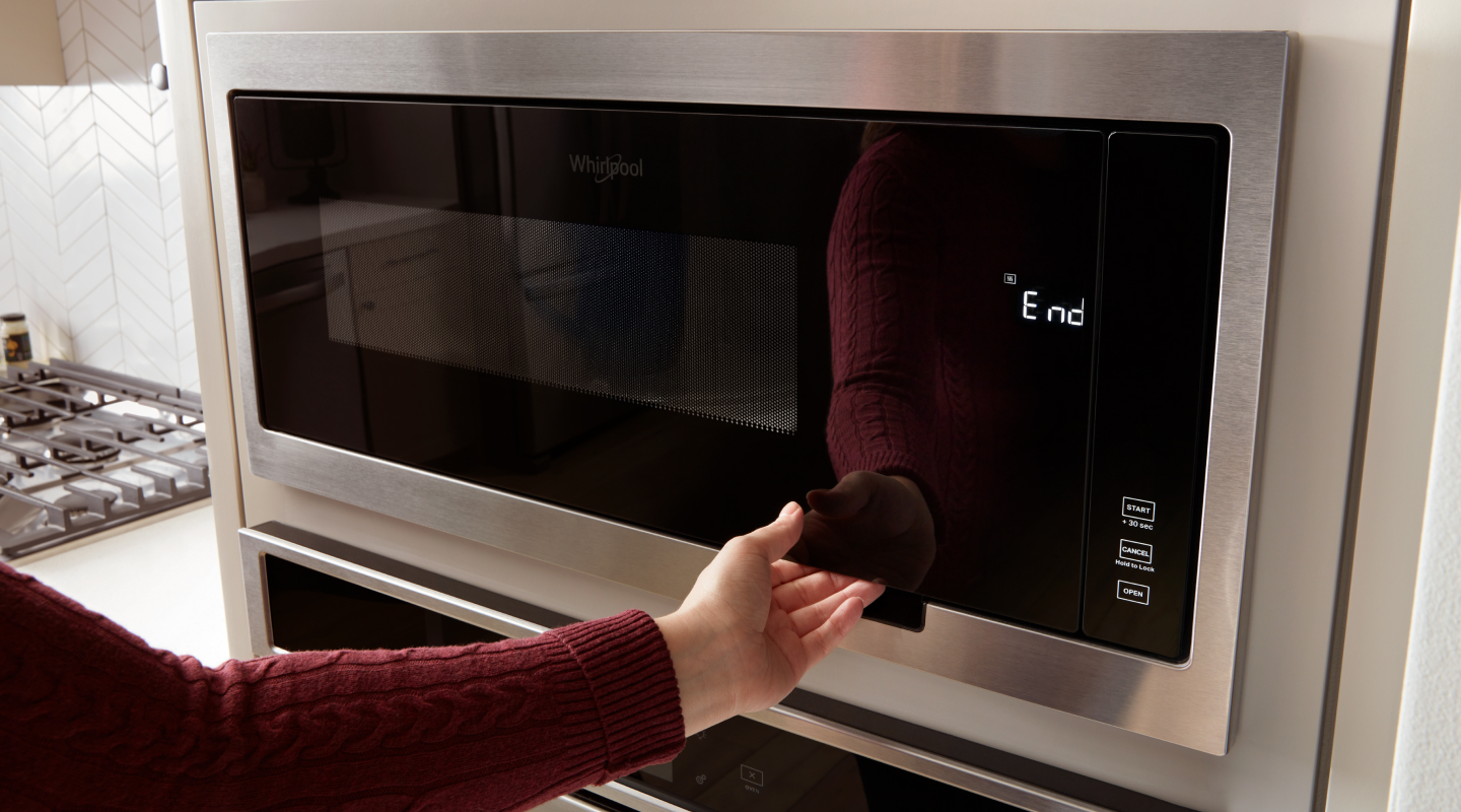 Person opening microwave cavity of Whirlpool® Combination Wall Oven