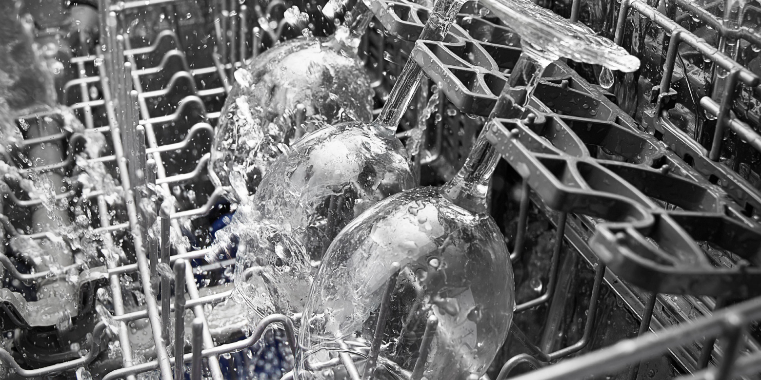 Close-up of wine glasses in dishwasher during wash cycle