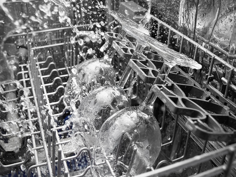 Close-up of wine glasses in dishwasher during wash cycle