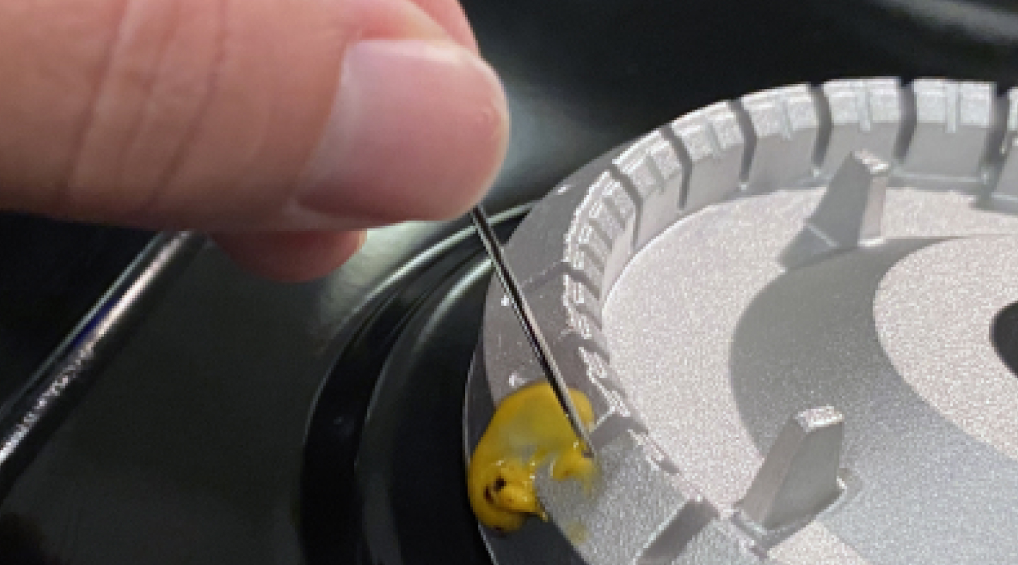 A person cleaning burner ports with a straight pin.