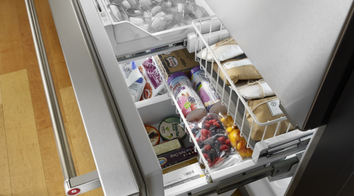 Shelves of food and an ice bin inside of a freezer