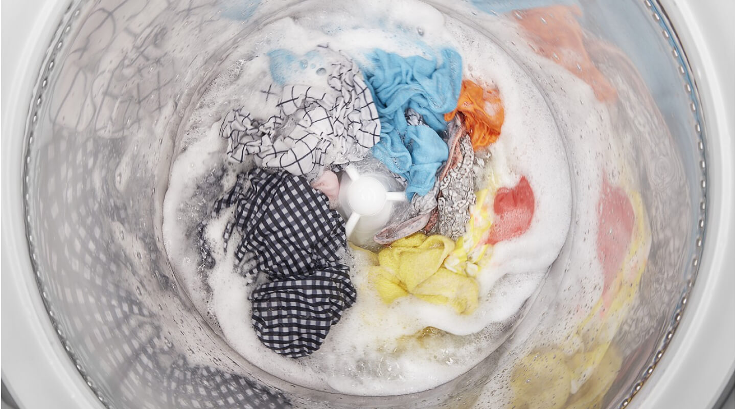 Top view of a washer agitating clothes in a soapy drum