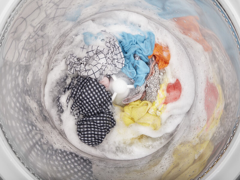 Top view of a washer agitating clothes in a soapy drum