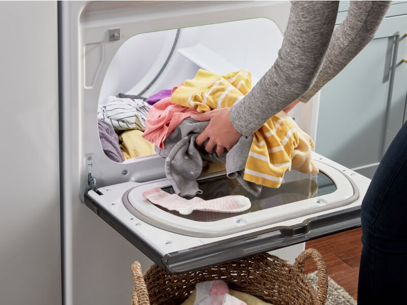 A person unloading laundry from a dryer
