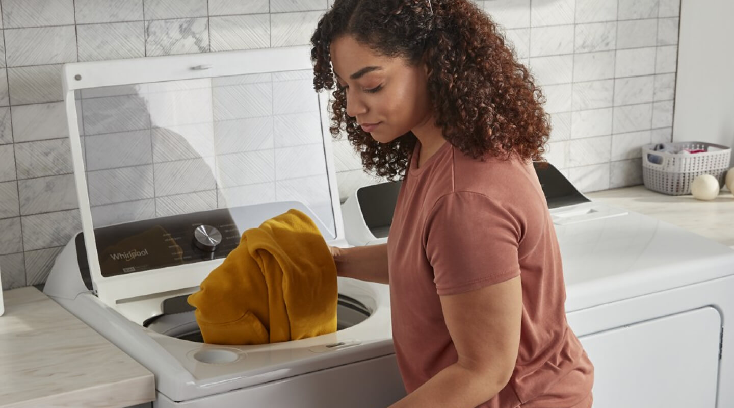 A person putting laundry in their washer