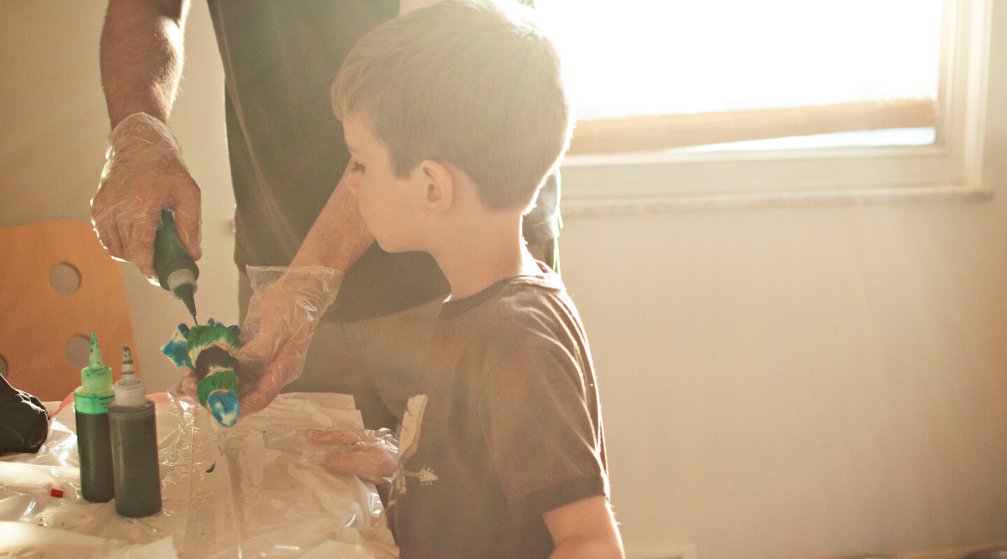 An adult and child crafting with paints