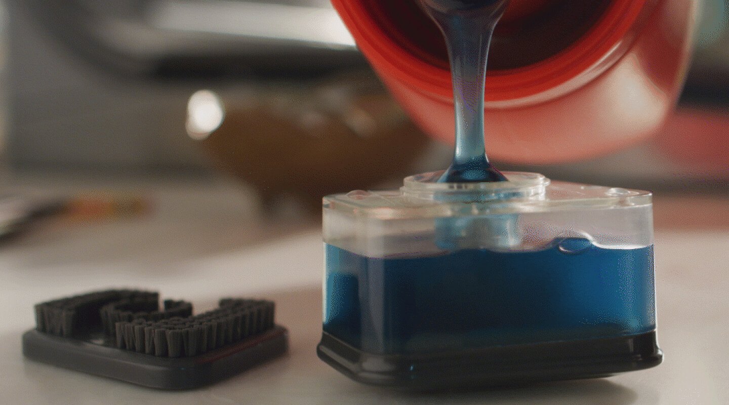 Person filling a stain spot treater with detergent
