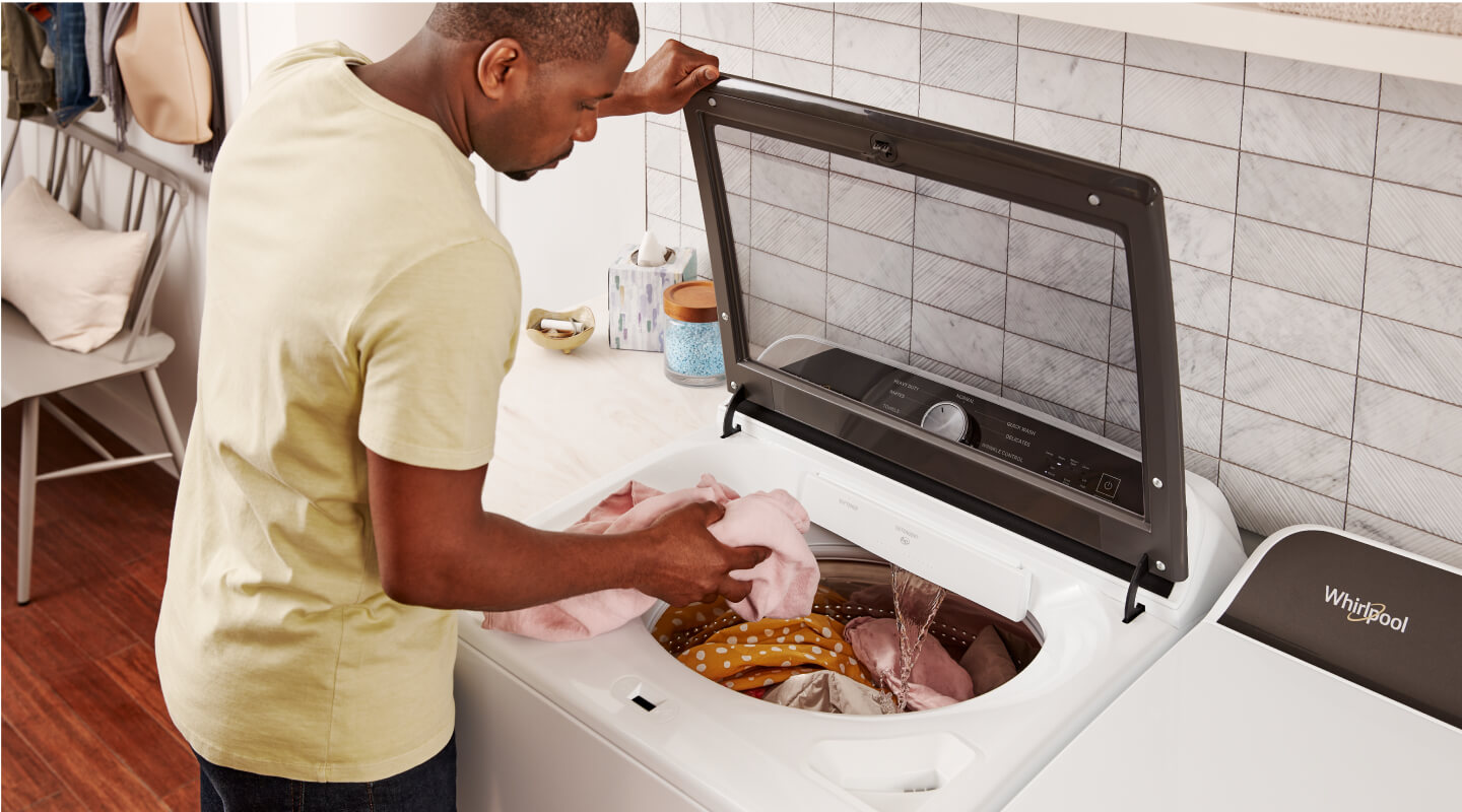 Person loading laundry into a Whirlpool® Top Load Washing Machine