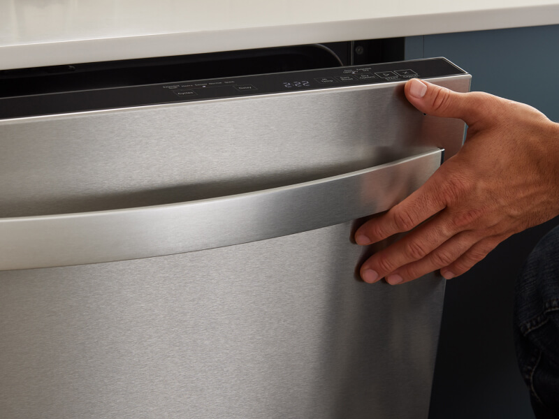 A close up of a hand closing a dishwasher door