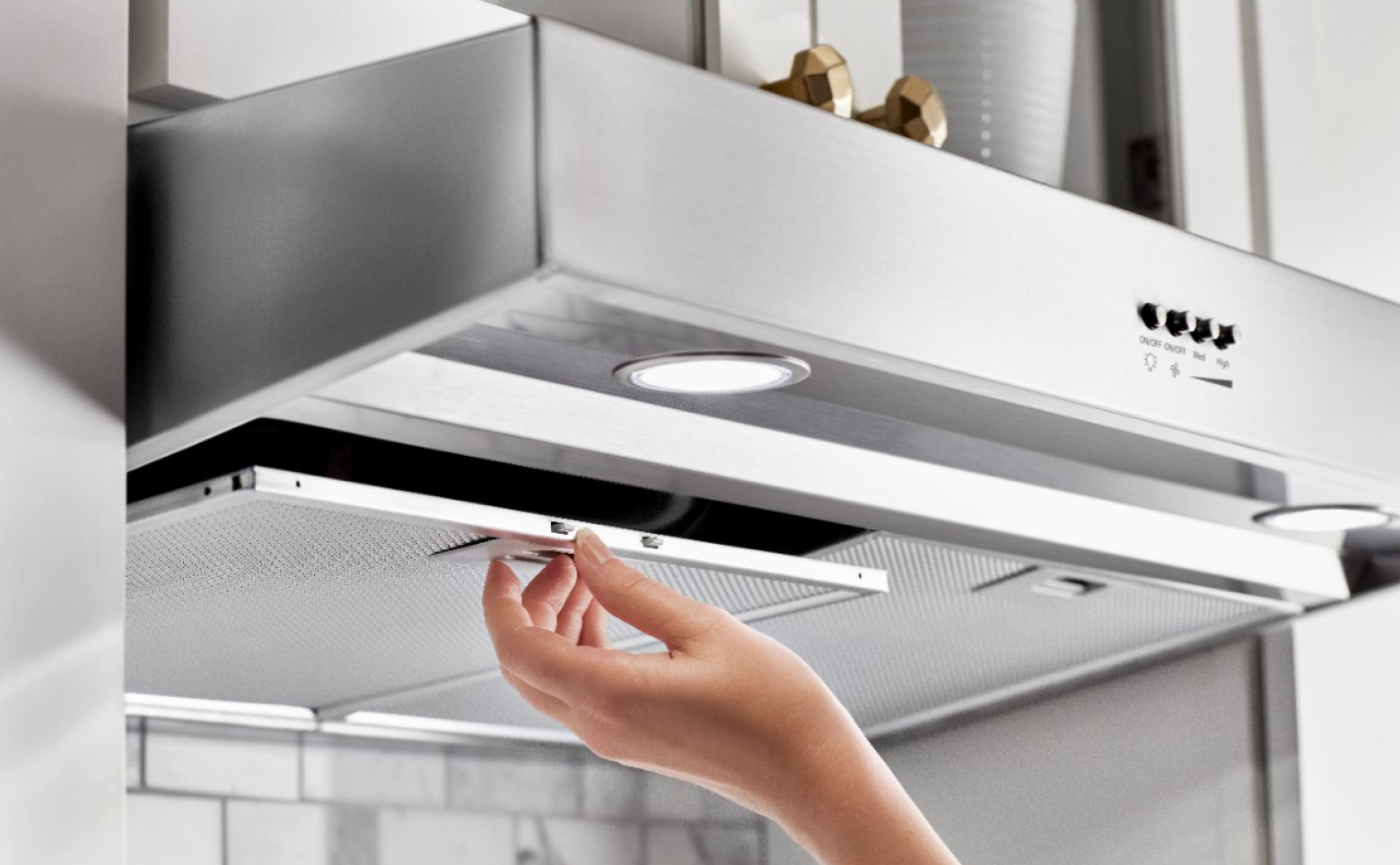 Hand replacing range hood filter 