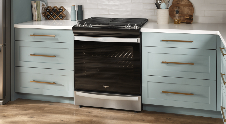 Black gas stove installed between teal cabinets