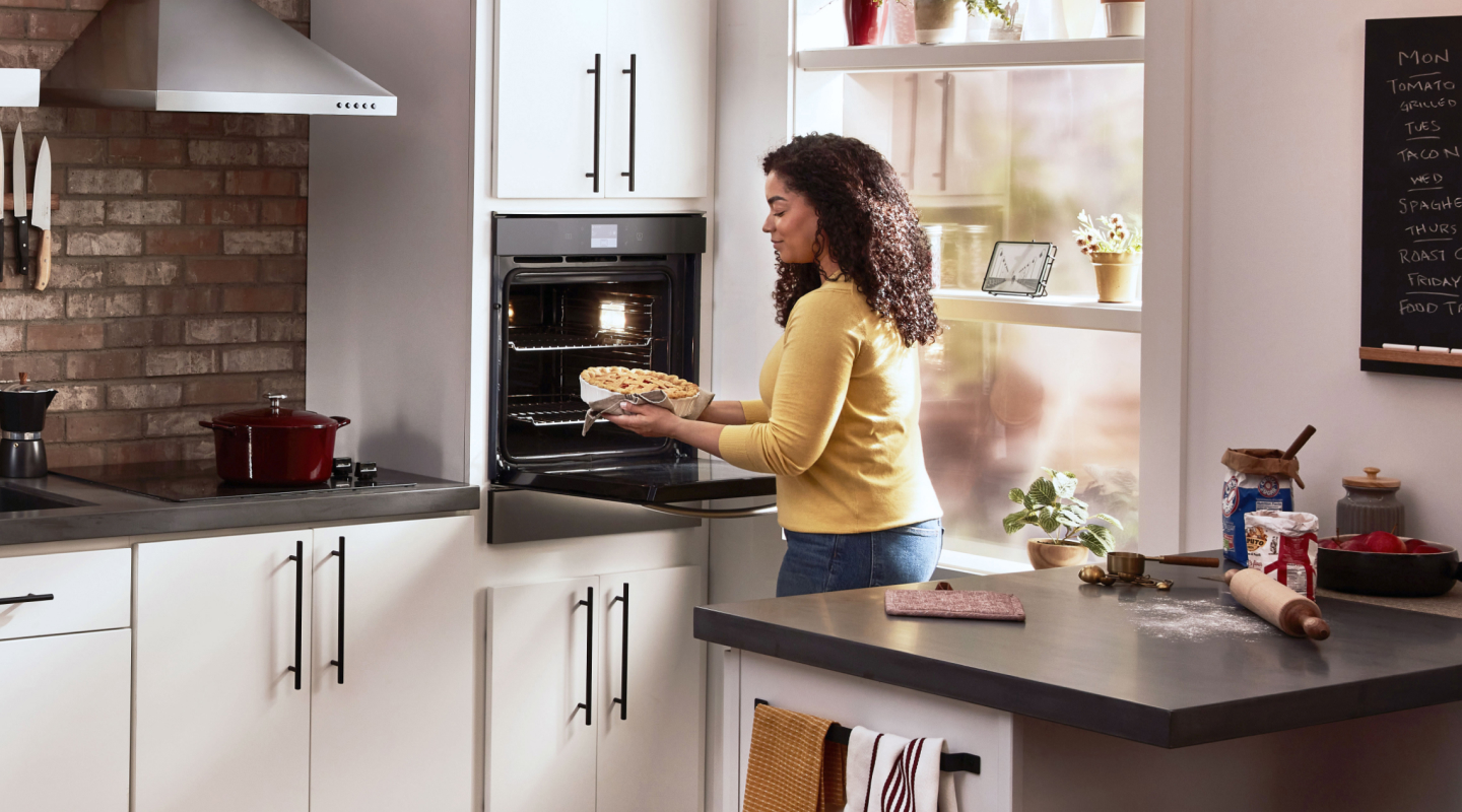 Woman using a Whirlpool®  single wall oven in a modern kitchen