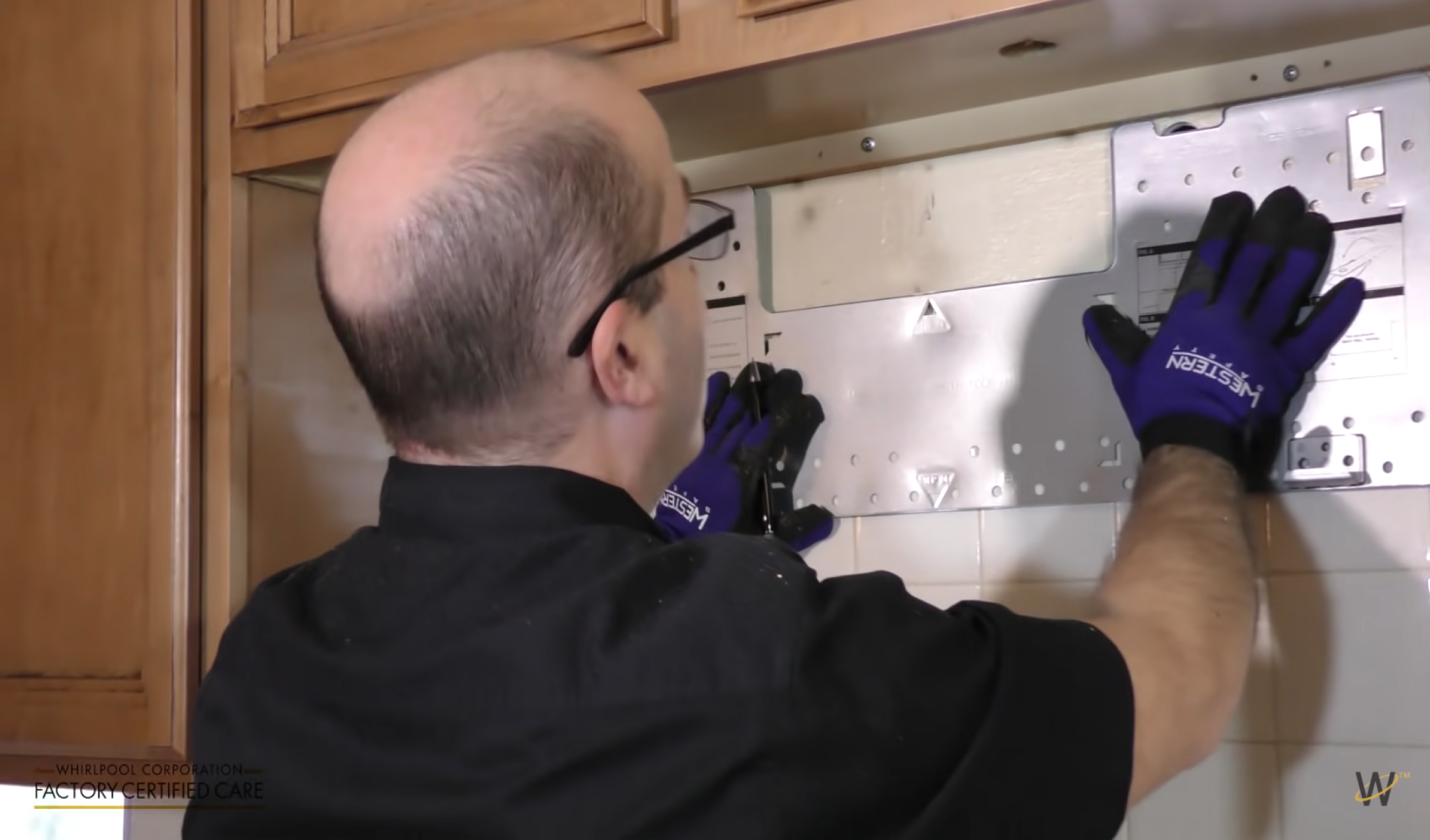 Person securely holding mounting plate against wall with two hands