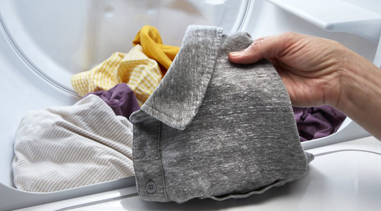 Person taking a gray shirt out of a dryer
