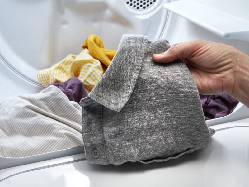 Person taking a gray shirt out of a dryer