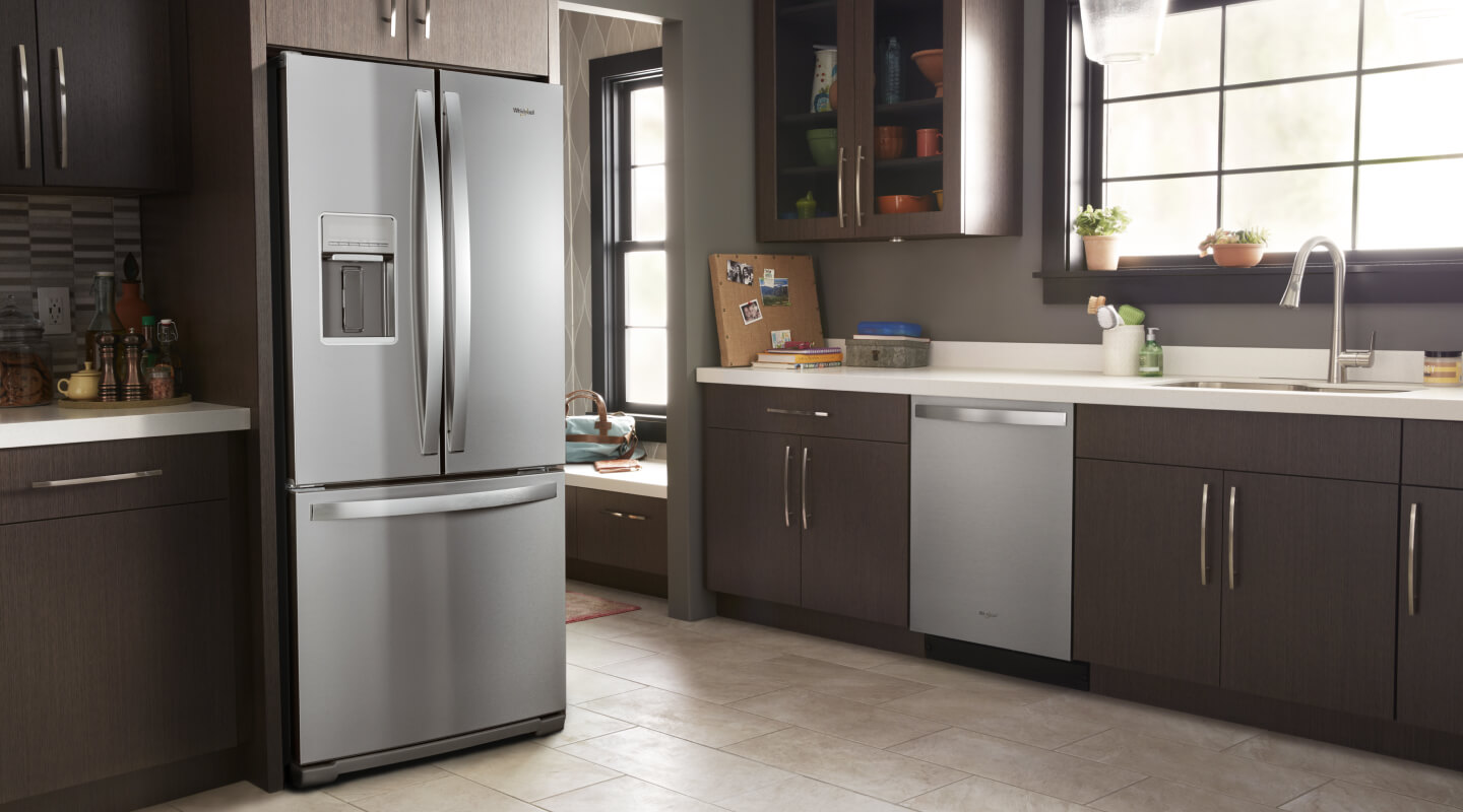 A stainless steel Whirlpool® French Door Refrigerator in a kitchen with dark cabinetry