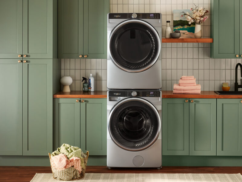 Stacked washer and dryer set in green cabinets