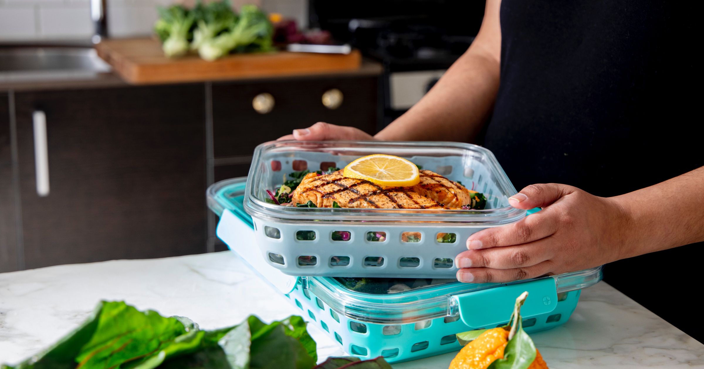 A container with a grilled chicken breast and slice of lemon.