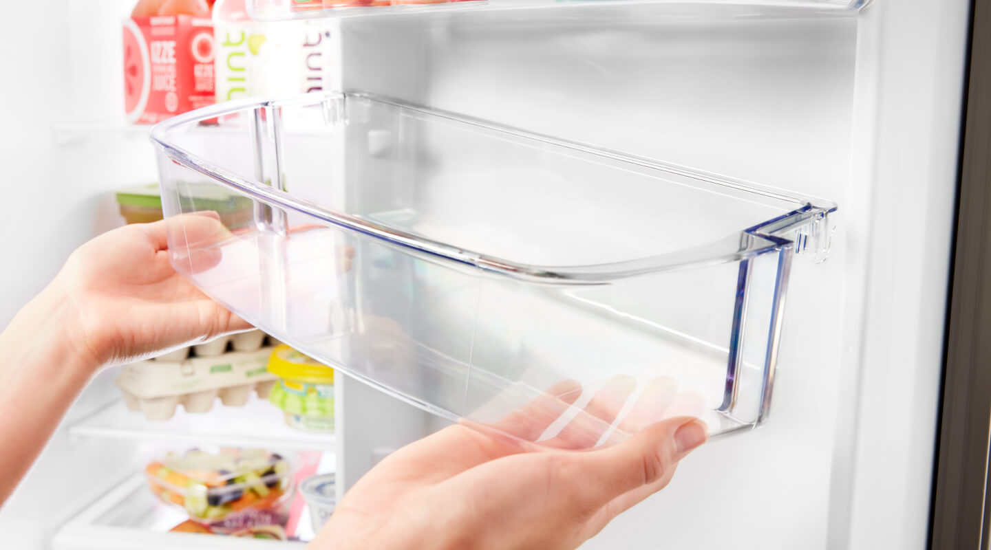 Person placing an empty refrigerator shelf in the refrigerator door