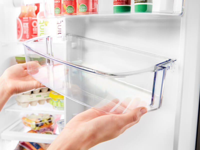 Person placing an empty refrigerator shelf in the refrigerator door