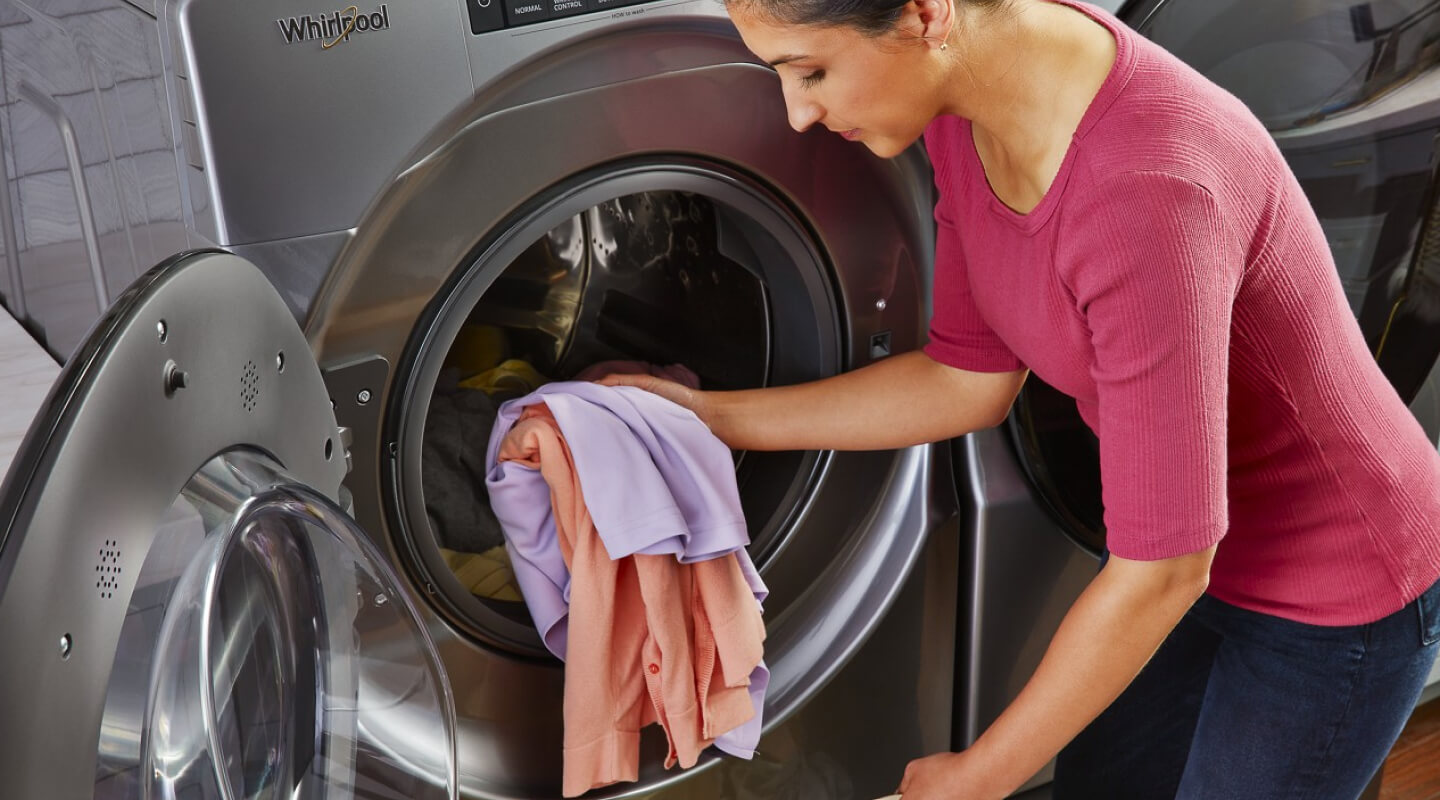 A person loading clothes into a Whirlpool® Front Load Washer