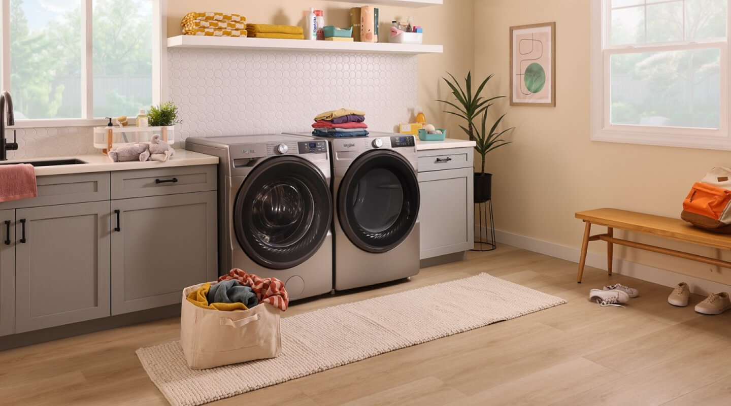 A bright laundry room with a bag of laundry on the floor in front of a Whirlpool® Washer and Dryer set