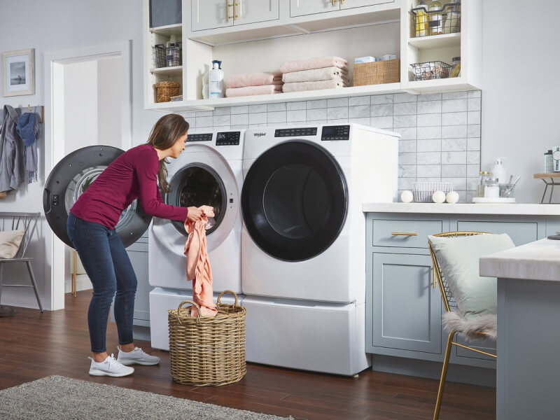 A woman loading clothes into a Whirlpool® Washer