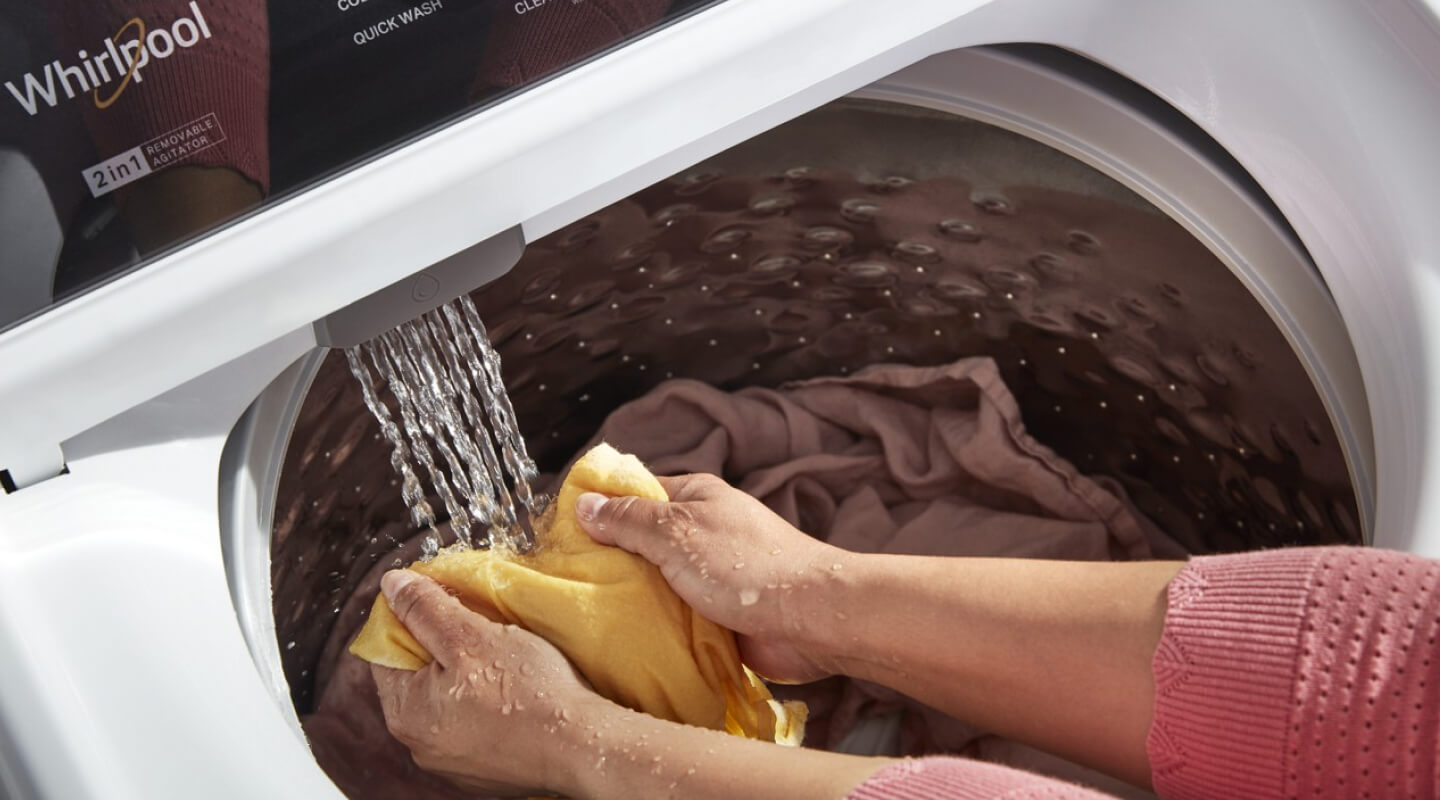 A person using the Built-In Water Faucet in their Whirlpool® Washer with 2 in 1 Removable Agitator