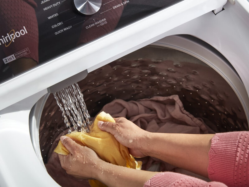 A person using the Built-In Water Faucet in their Whirlpool® Washer with 2 in 1 Removable Agitator