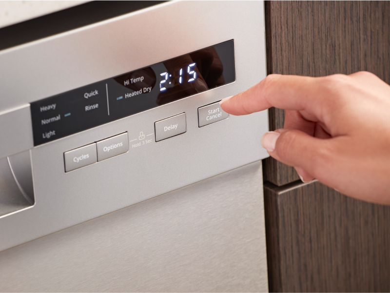 Person selecting wash cycle options on dishwasher control panel