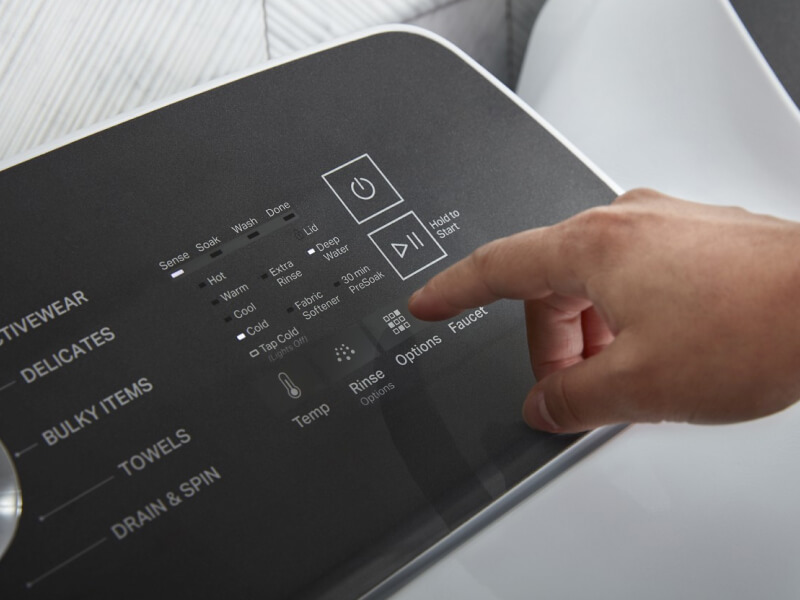 Person about to push a button on a washing machine