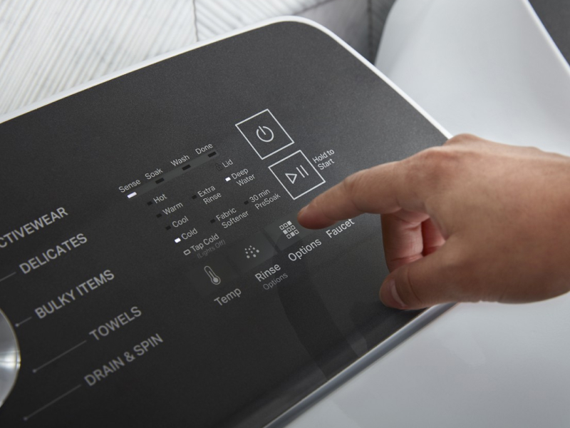 Person selecting settings on a washer control panel