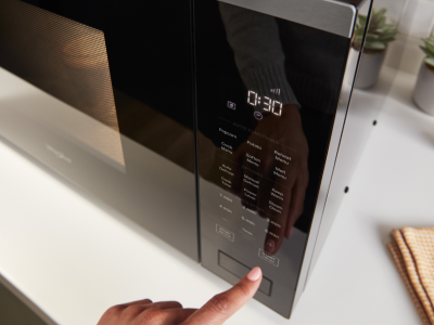 Person operating the control panel of a microwave