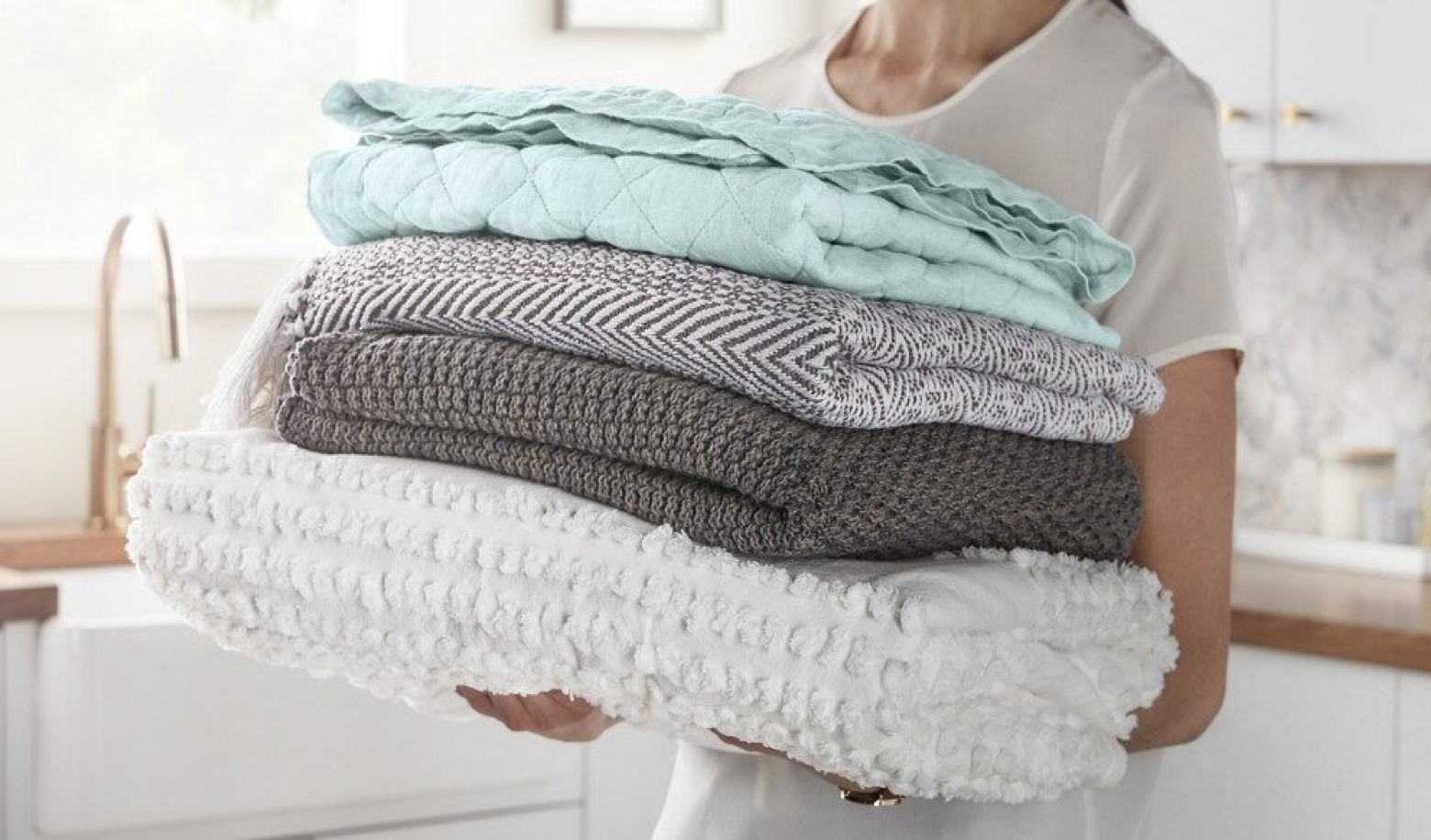 Woman carrying a stack of folded blankets