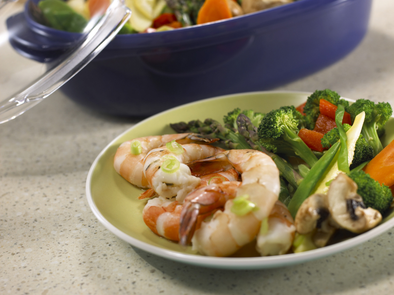 Steamed vegetables on a plate with grilled shrimp