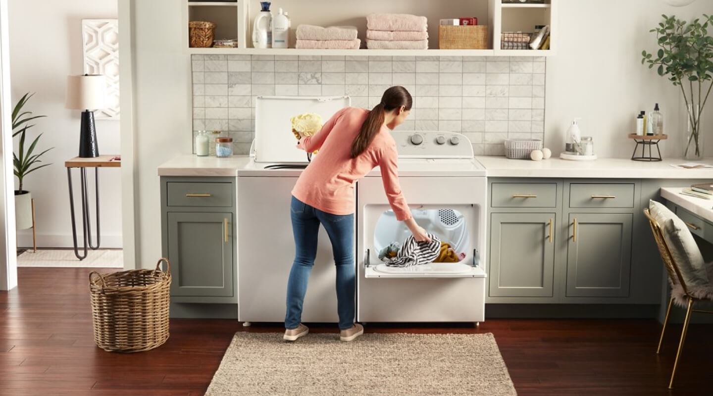 Person moving laundry from a washer to a dryer